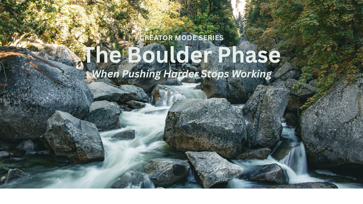 River flowing around large boulders in a forest, symbolizing movement through resistance and the transition from effort to flow